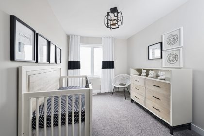 Bright second bedroom with plush carpeting, pictured here as a nursery.