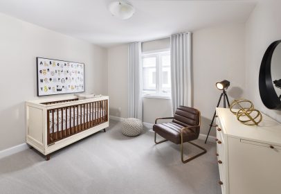 Baby's bedroom with cream and wood crib, brown leather chair and cream dressser with gold accessories