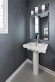 The Powder Room features pedestal sink with a single lever chrome faucet and grey textured wallpaper.