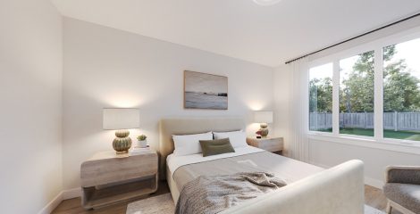 Primary bedroom in creams with bed, nightstands and view to backyard.